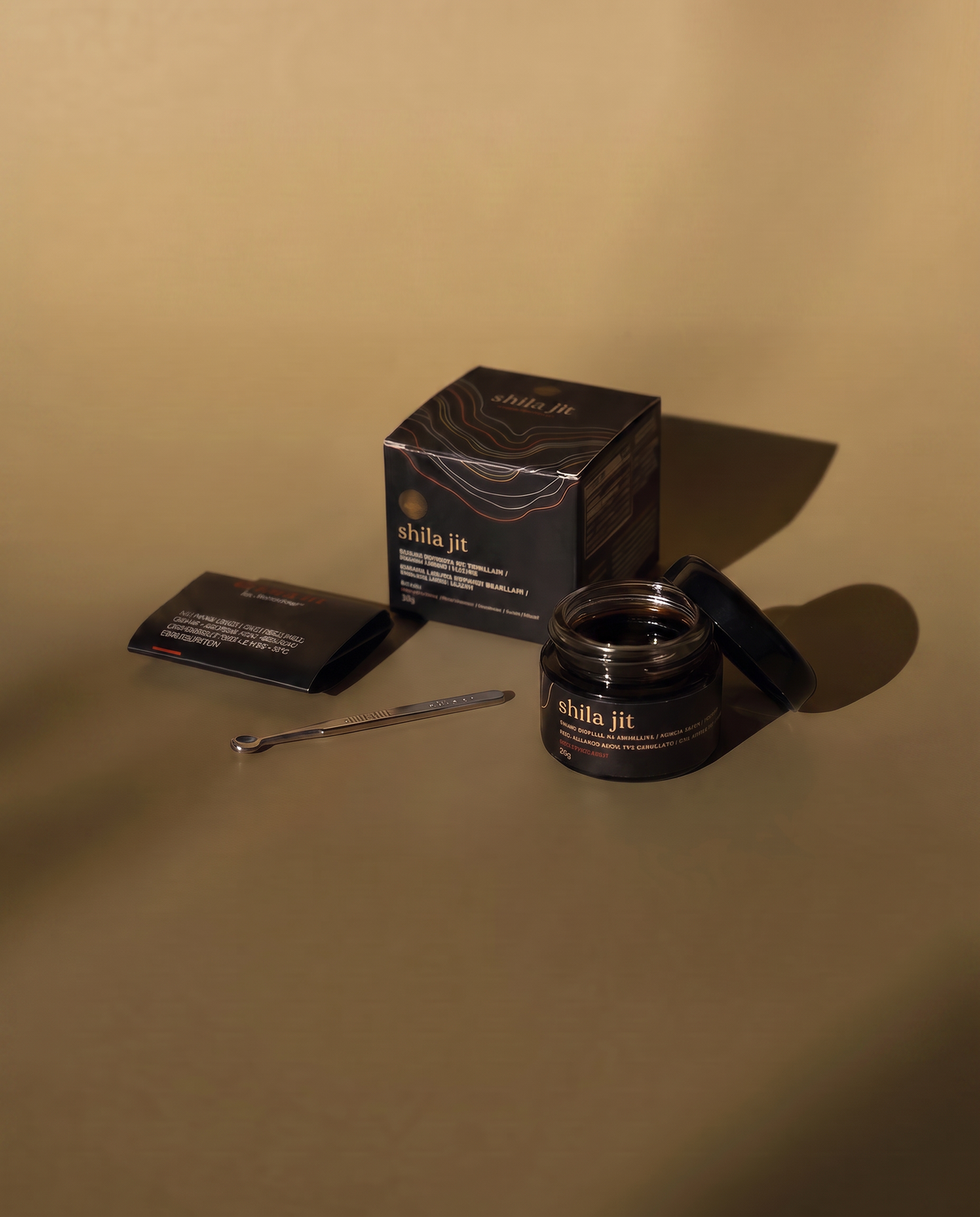 Primer plano de Bionobo  golden Shilajit resina extraída de un frasco abierto con una cuchara dosificadora.