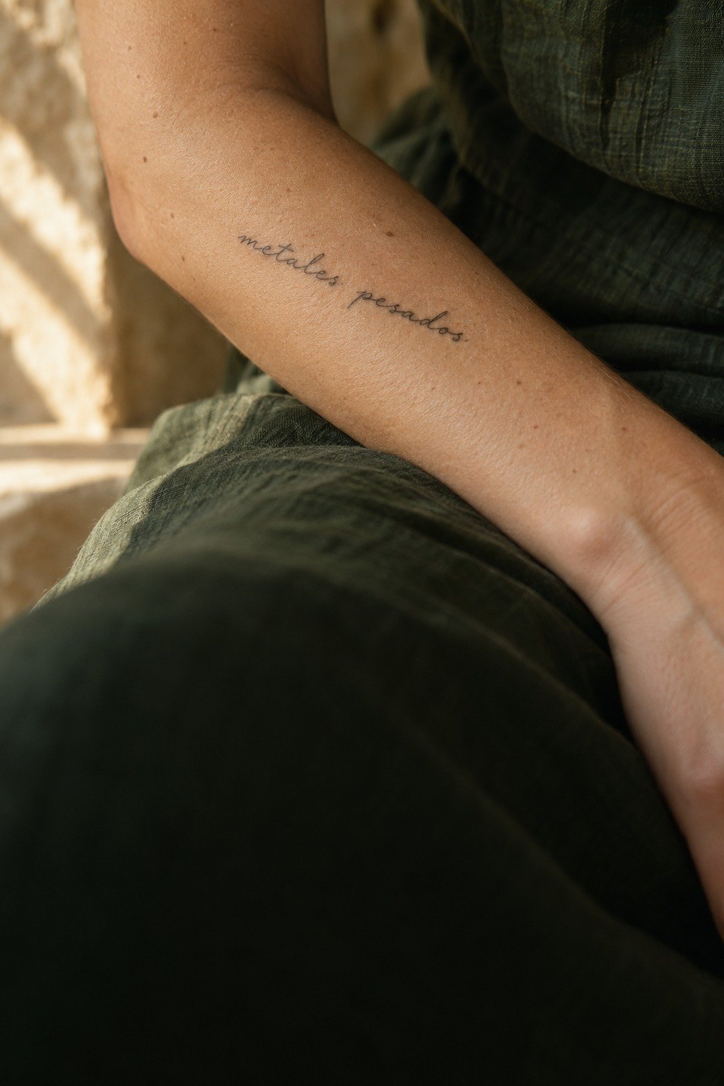 A forearm with a small handwritten tattoo