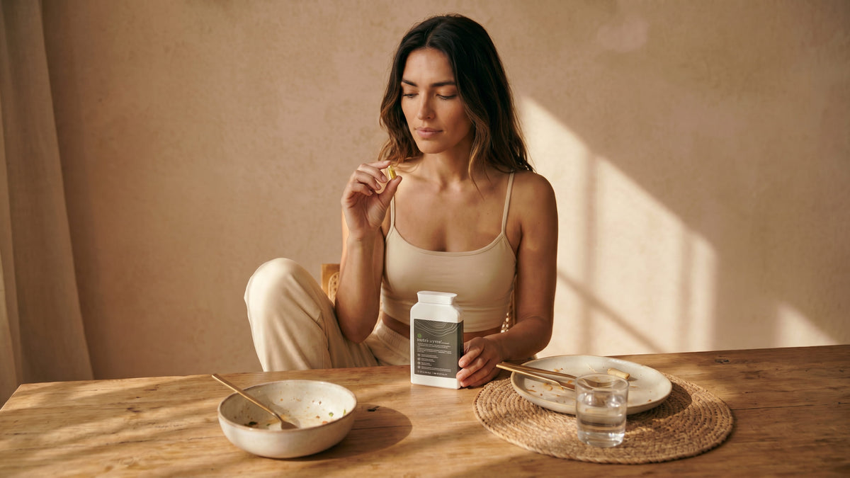Cápsulas nutri:zyme® junto a un plato de comida en la mesa